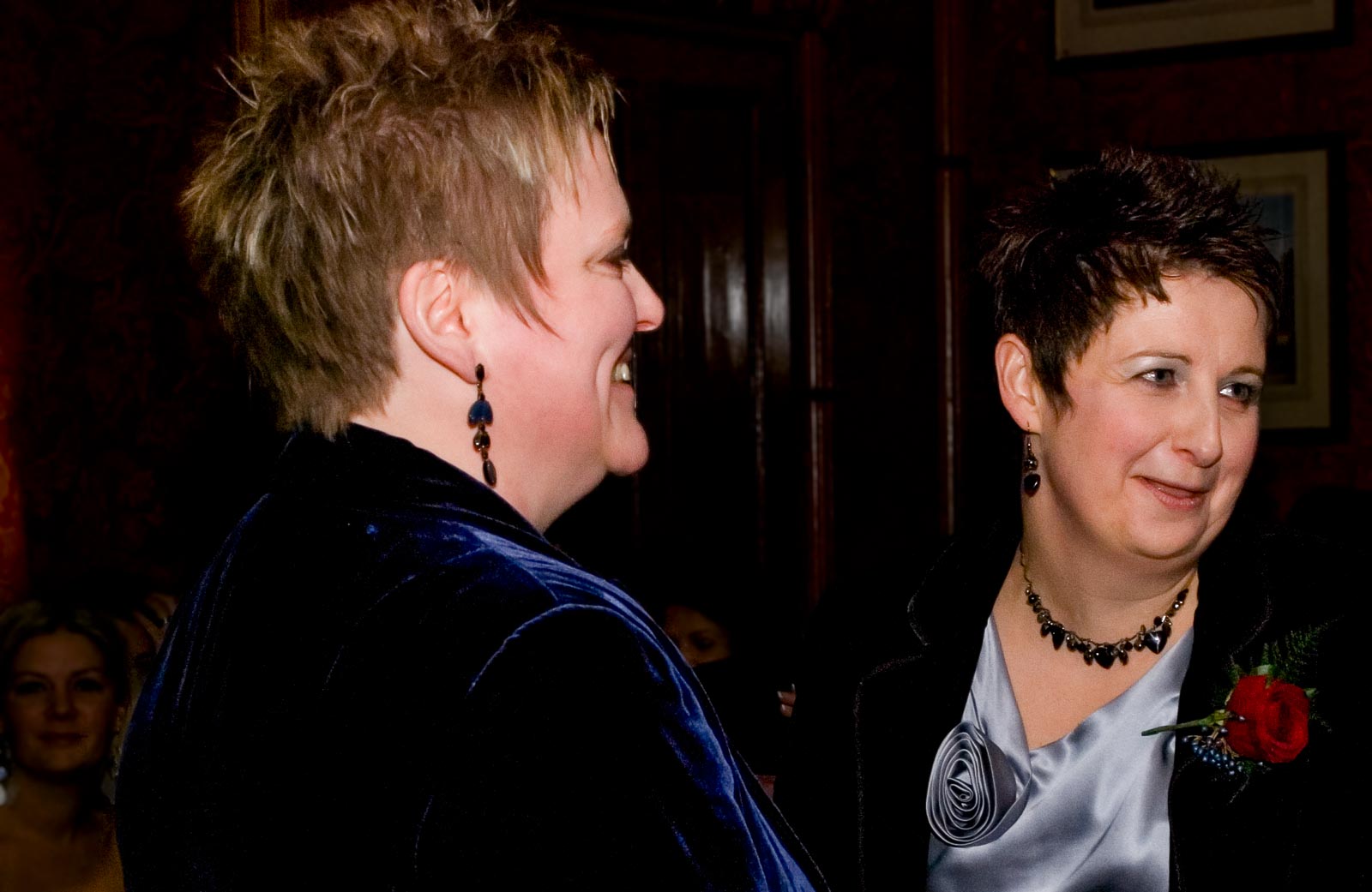 Laura and Paula laugh surrounded by guests inside Brighton Dome during their civil partnership.