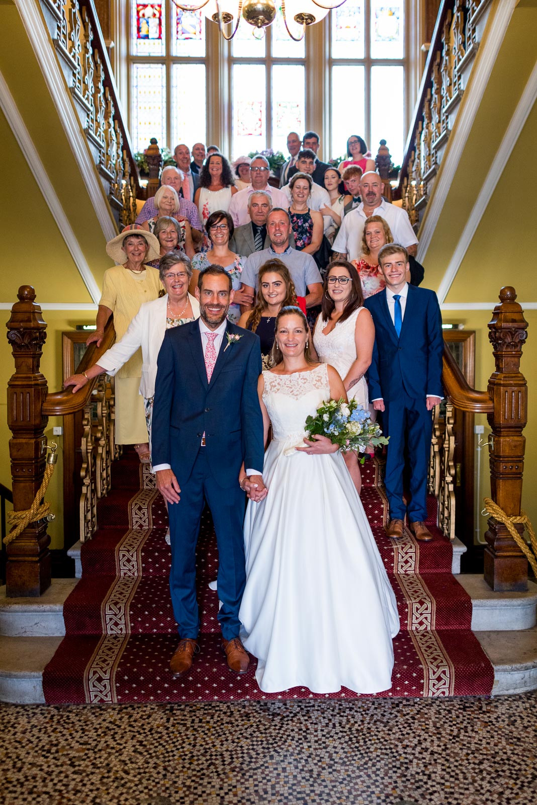 Donna, Andy and the couples wedding guests are photographed on the stairs at Eastbourne Town Hall.