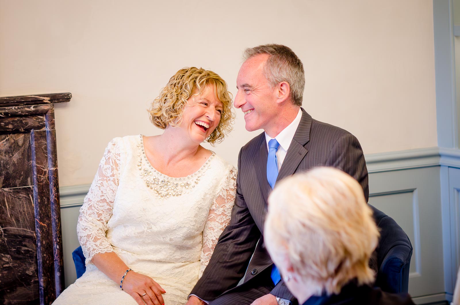 Wendy and Chris laugh in the Evelyn Room at Lewes Register Office during their wedding.