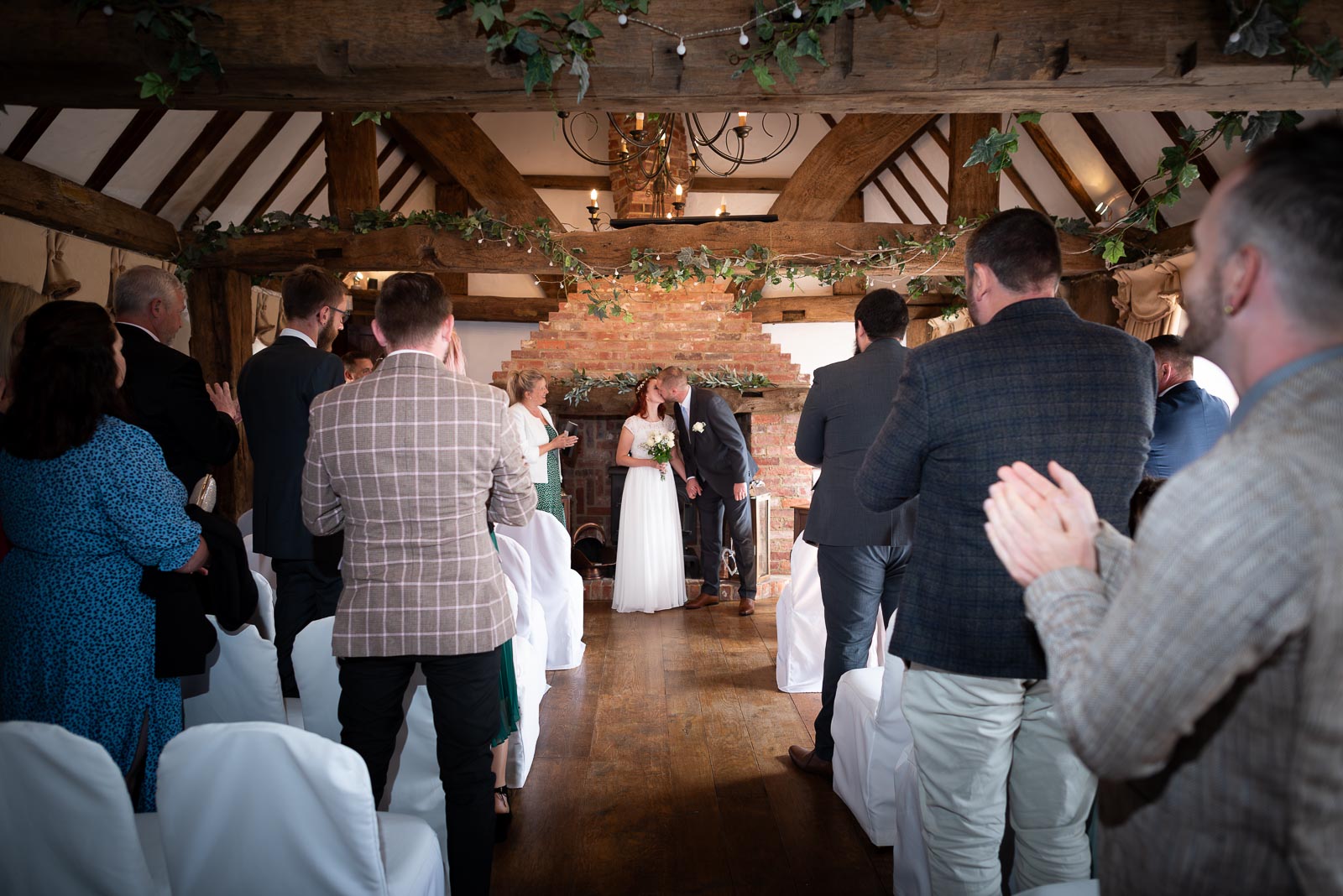 Friends and family clap and cheer as Adrienn and Lee embrace at the top of the aisle at Milwards Farm Estate near Lewes after getting married.