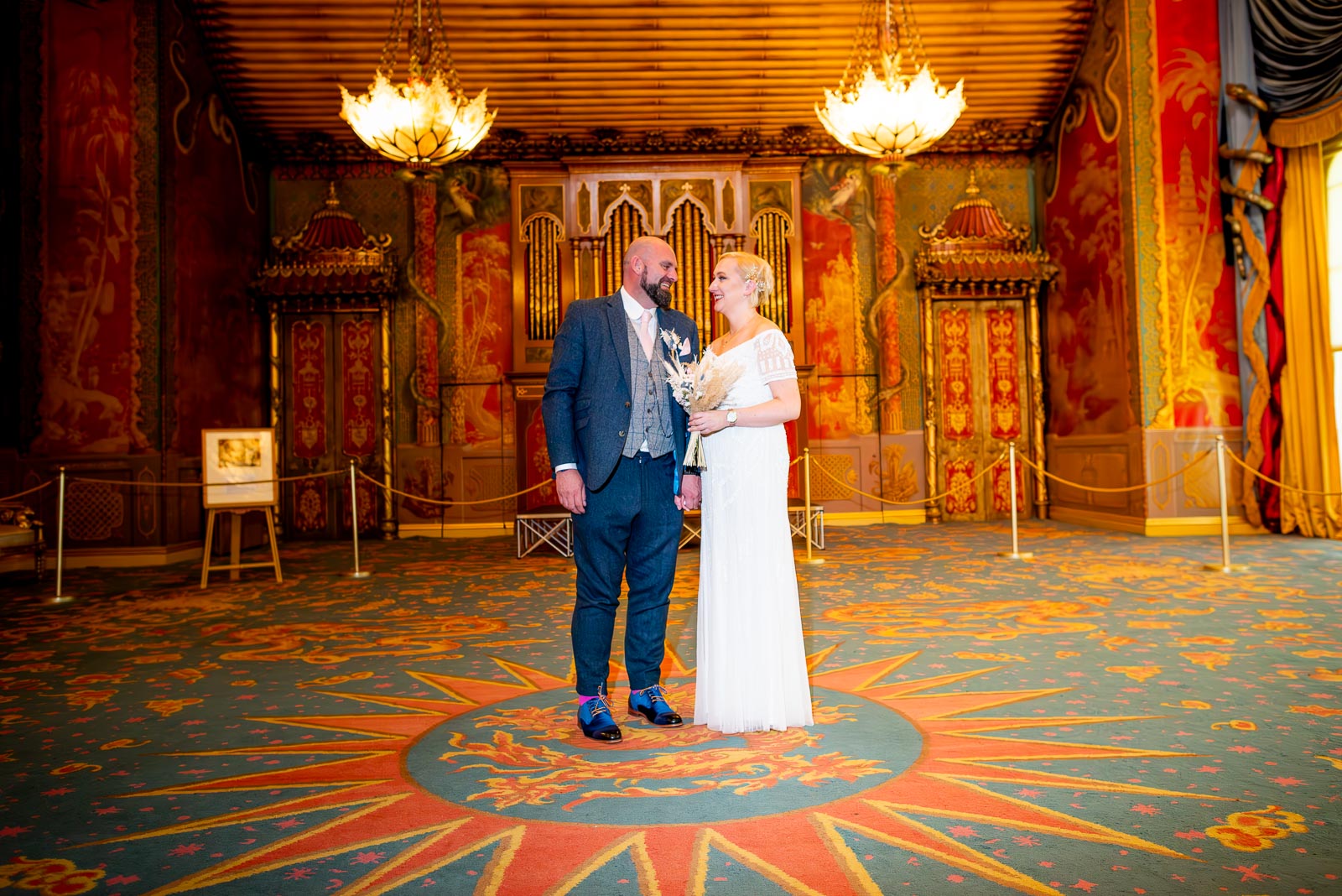 Georgina and Andy smile in the beautifully decorated Music Room in Brighton Royal Pavilion after their wedding.