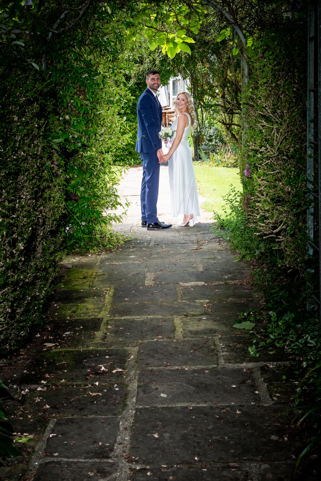 Fred and Jess pose in one of the leafed arches of Horsted Place Hotel's garden.