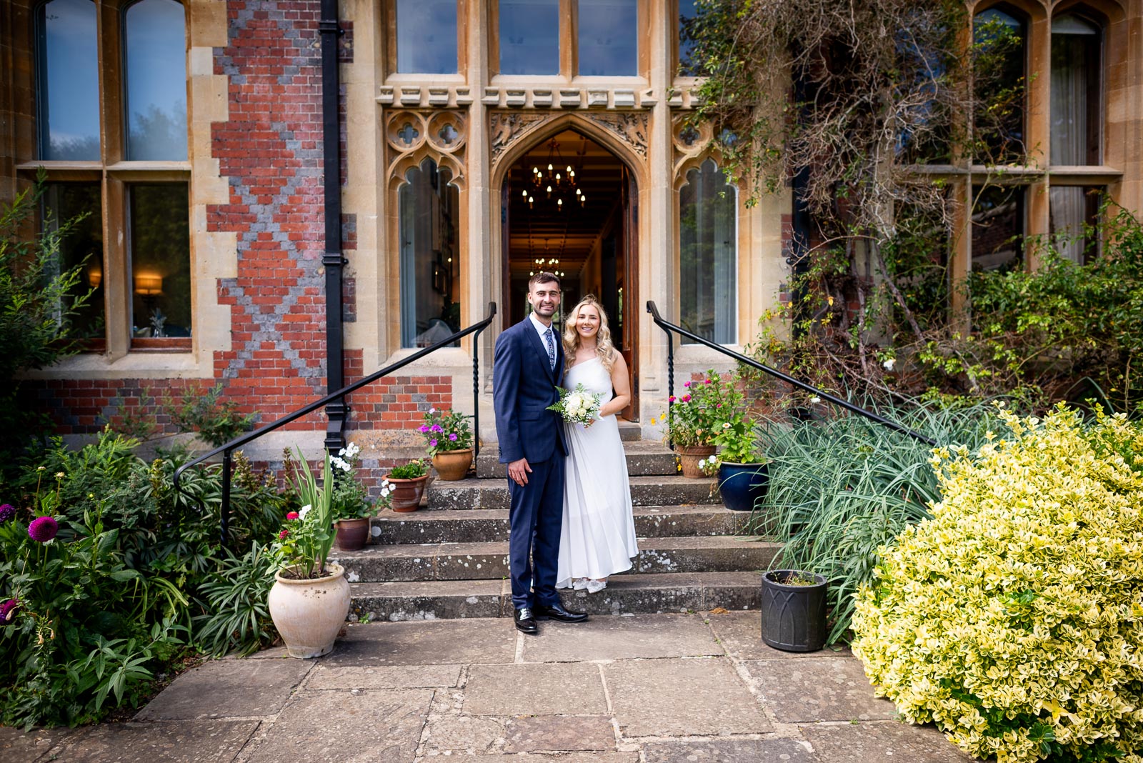 Jess and Fred pose at the back entrance of Horsted Place Hotel after their wedding.